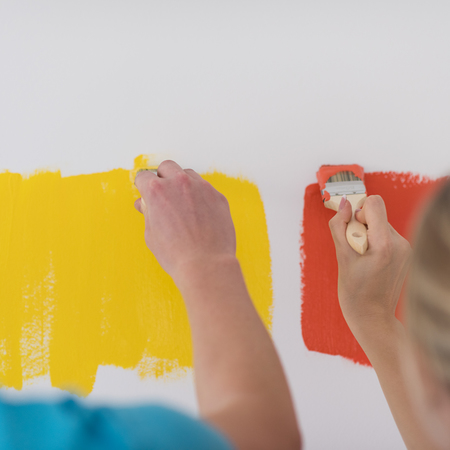 happy smiling young couple painting interior wall of new house